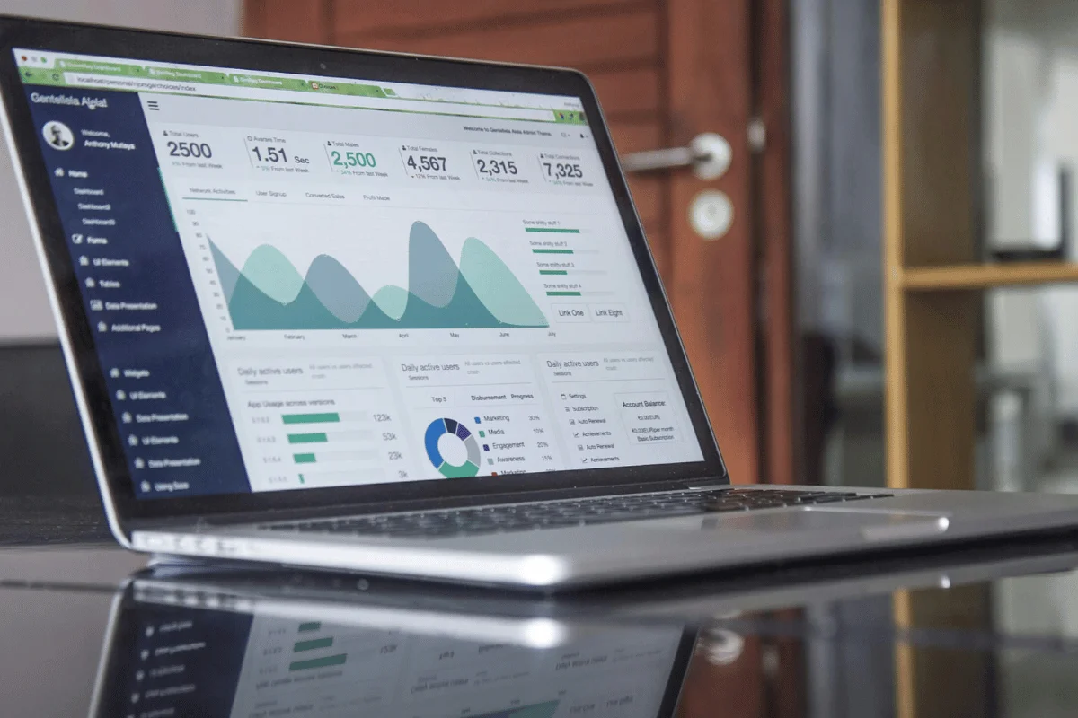 A laptop displays an analytics dashboard with graphs and statistics on user activity, engagement, and app usage metrics.