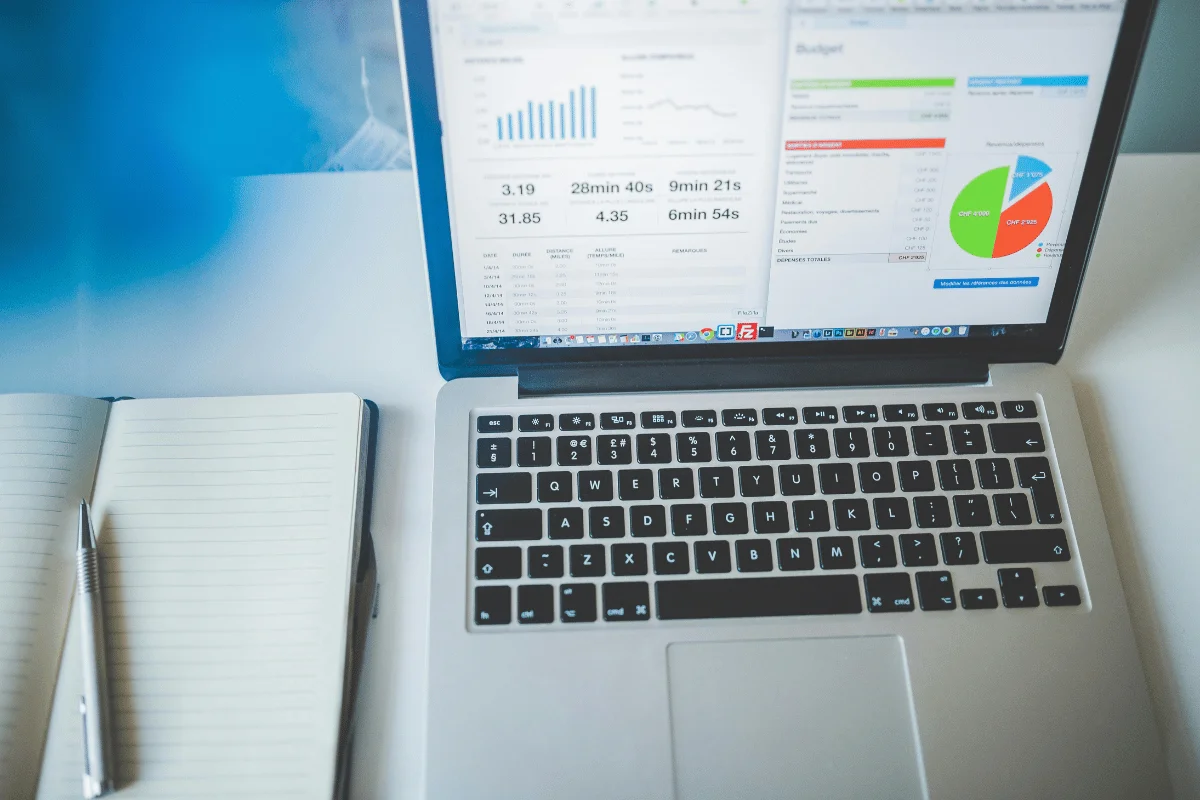 Business analytics dashboard on laptop screen with notebook on modern desk